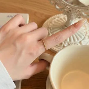 Gros plan d'une bague fine en or minimaliste avec trois diamants sur un doigt féminin.