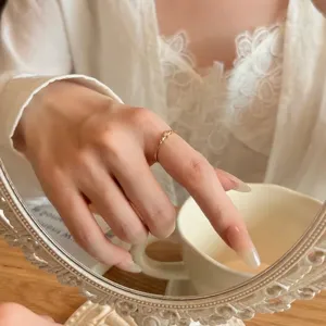 Gros plan d'une bague minimaliste dorée délicate ornée de trois petits diamants brillants