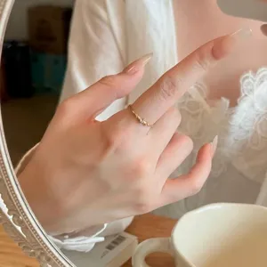 Gros plan d'une bague minimaliste en acier titane avec trois pierres brillantes dorées