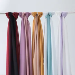Close-up detail of assorted solid and gradient chiffon scarves hanging for display