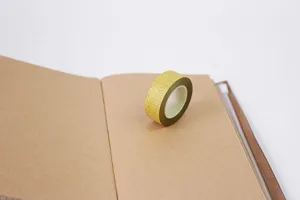 Gold glitter washi tape detail view on kraft notebook, ideal for creative journaling.