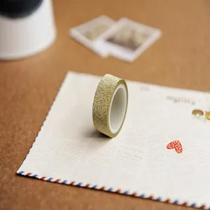 Close-up view of gold glitter washi tape placed on vintage envelope paper for DIY crafts.