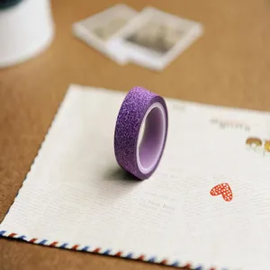 Close-up of purple glitter washi tape on vintage letter paper, perfect for DIY journaling crafts.