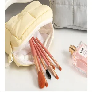 Detailaufnahme der gesteppten, wasserdichten Kosmetiktasche in Gelb mit Make-up-Pinseln.