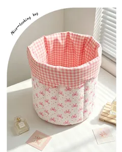 Close-up of pink quilted fabric storage basket with cute bow pattern for desktop organization.