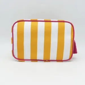 Striped cosmetic bag detail featuring yellow-white pattern and pink tassel zipper pull accent.
