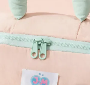 Primer plano detallado de neceser de maquillaje marshmallow, tela acolchada rosa con cremalleras.