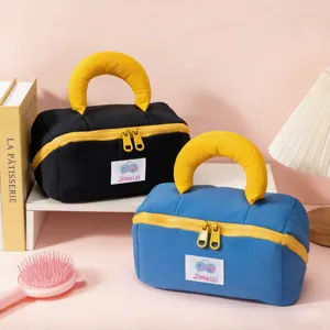 Vista detallada de grandes bolsas cosméticas en negro y azul con asas y cremalleras amarillas.