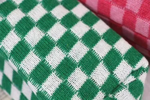 Détail de trousse de maquillage en tricot à carreaux vert et blanc, gros plan pochette.