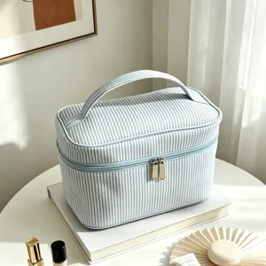 Détail de la trousse de toilette rayée bleue et blanche avec grande capacité et poignée pratique.