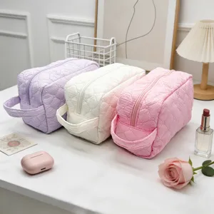 Quilted cosmetic bag detailed view showing fine textured fabric, zipper closure and handy side handle.