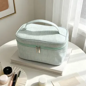 Détail de trousse de maquillage rayée vert menthe, pochette en tissu avec double fermeture.