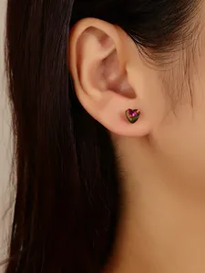 Close-up detail of a sparkling multi-color crystal heart stud earring worn on the earlobe.