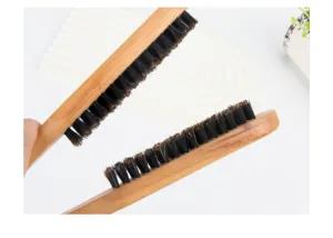 Primo piano dettagliato della spazzola per capelli in legno a V con setole naturali.