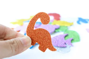 Close-up detail of glitter orange dinosaur EVA foam sticker for kids DIY crafts and handmade art.