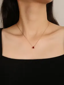 Close-up detail of a delicate birthstone necklace with a sparkling red zircon pendant.