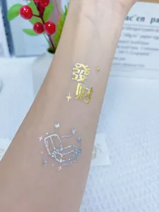 Close-up detail of metallic gold and silver temporary tattoo sticker on skin, elegant design.