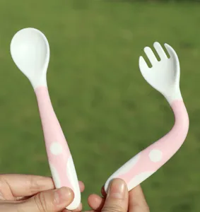 Primo piano dettagliato del set cucchiaio e forchetta flessibili per neonati rosa e bianco.