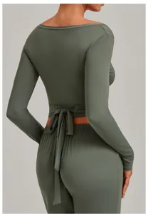 Back view detail of green long-sleeve crop yoga top with wrap tie waist and pants.