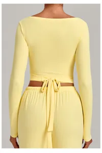 Back view detail of yellow long sleeve wrap yoga top with waist tie and matching pants.