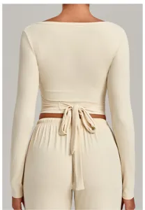 Detailed back view of beige long sleeve crop top featuring wrap around back ties.
