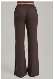 Detail view of back wearing brown loose straight yoga pants with elastic waist drape.