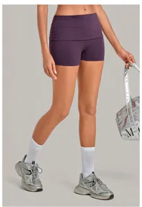 Detailed view of women's purple folded waistband yoga shorts paired with stylish silver sneakers.