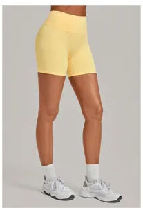 Primo piano di pantaloncini da yoga gialli a vita alta con tessuto liscio e stile sportivo.