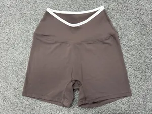 Brown cross-waist yoga shorts with white trim. Tight quick-drying athletic shorts for gym and running.