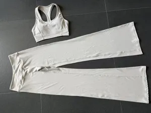 Vue à plat détaillée de l'ensemble de yoga extensible blanc respirant, haut et pantalon.
