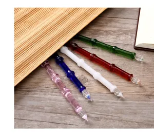 Vue détaillée de stylos-plume en verre cristal coloré faits à la main sur table en bois avec natte.