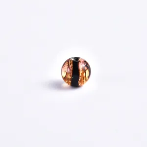 Close-up detail of a transparent glass bead with golden flakes and dark stripe for DIY jewelry.