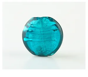 Close-up of a vibrant turquoise glass DIY bead with inner foil texture, perfect for crafts.