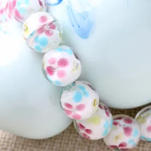 Close-up detail of handmade glass flower beads, colorful petal pattern inside clear beads.