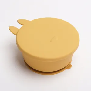 Vista dettagliata della ciotola in silicone giallo per neonati con coperchio e orecchie.