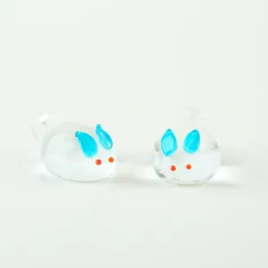 Close-up detail of cute glass rabbit charm pendant with blue ears for DIY jewelry making.