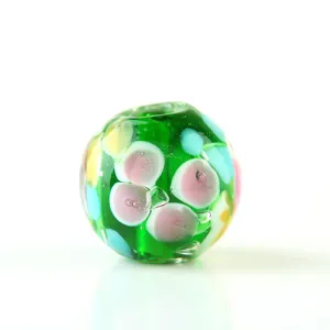 Handcrafted green glass bead detail showing colorful floral inner patterns for DIY jewelry making.