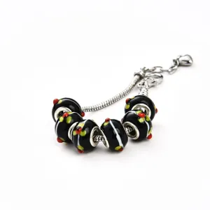 Silbernes Schlangenkettenarmband mit schwarzen Glasperlen, weißen Streifen und bunten Punkten.