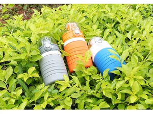 Detail view of colorful silicone collapsible water bottles outdoors in green leaves, portable design.