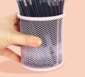 Close-up detail of pink metal mesh pen holder filled with black gel pens for desk organization.
