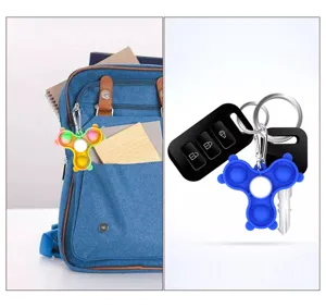Scene detail of pop it fidget spinner keychain attached to backpack and keys for stress relief.