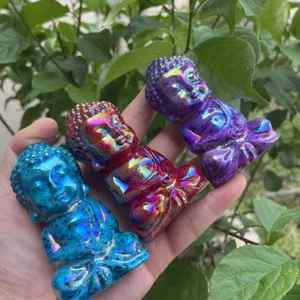 Nahaufnahme der Hand mit drei lebendigen Auras-Kristall geschnitzten Buddha-Figuren.