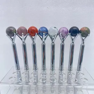Close-up view of natural crystal sphere metal ballpoint pens displayed on clear acrylic stand.