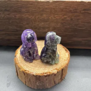 Nahaufnahme von handgeschnitzten Kristallstein-Welpenfiguren auf einer Holzscheibe.