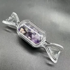 Detailaufnahme einer klaren Glasflasche in Bonbonform, gefüllt mit lila Amethyst-Steinen.
