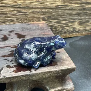 Gros plan detail de vue de sculpture de grenouille en cristal bleu sur support en bois.