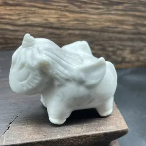 Close-up detail of white crystal unicorn carving, smooth polished gemstone finish texture.