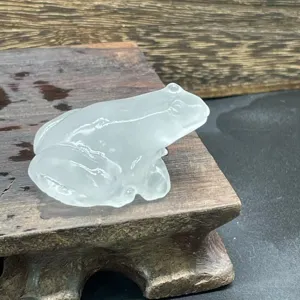Gros plan detaille de la grenouille en cristal sculptee, montrant texture lisse et beau travail.