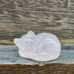 Gros plan détaillé d'une sculpture de chat endormi en cristal rose, surface polie, gemme.