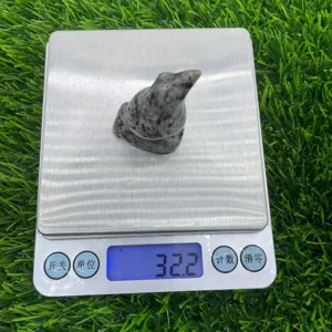 Detailed shot of a hand-carved gemstone raven figurine placed on a digital scale, natural stone texture.